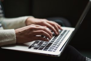 Close-up of a hand typing on a laptop keyboard